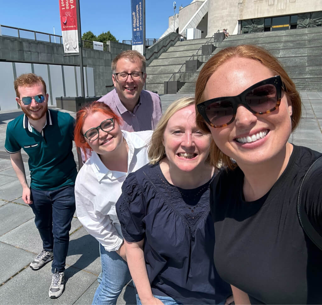 A group of teammates smiling while playing a city based treasure hunt on a team building day