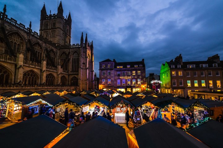 Stalls in wooden huts with Bath abbey in the background